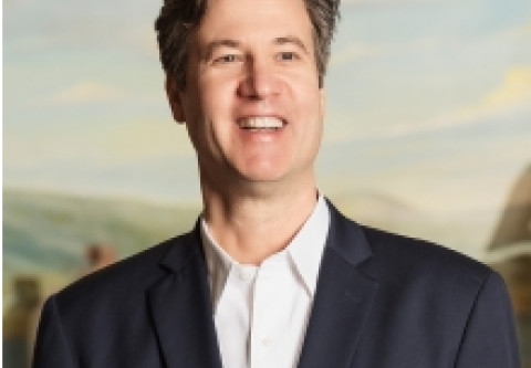 Headshot of Peter Stuck, a white man with dark hair wearing a white shirt and dark suit