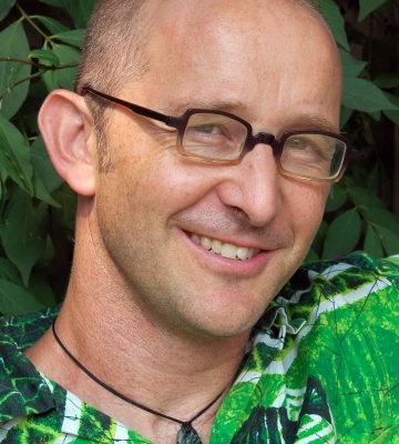  Head shot of Cam Grey, a whit man with glasses and a green button up shirt